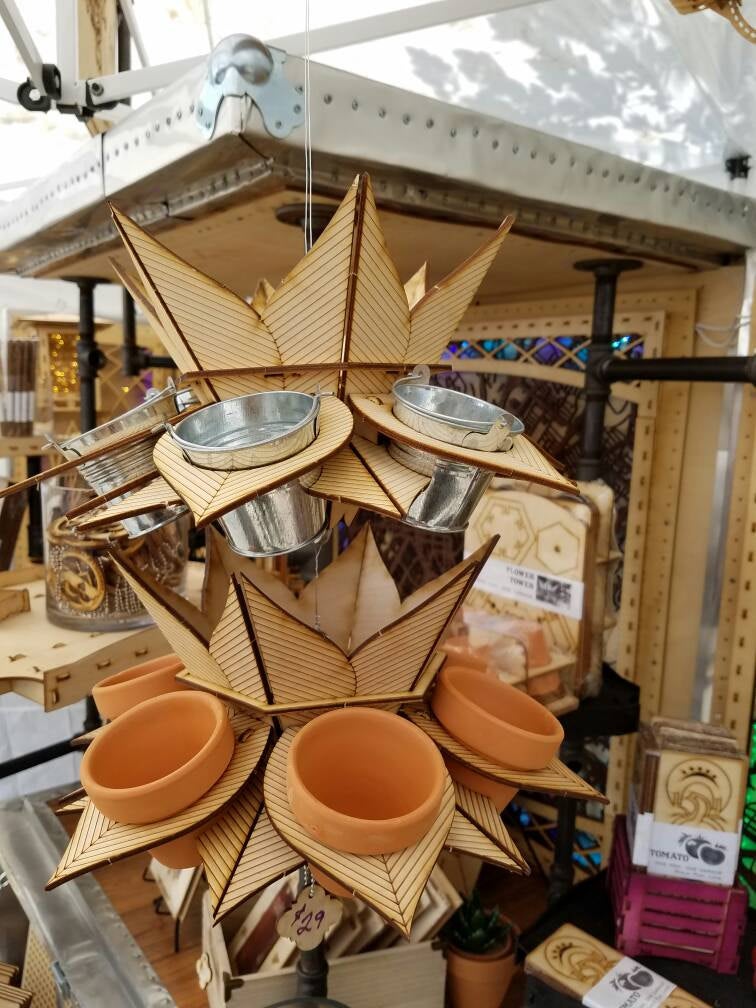 double stack of vertical hanging planter display with multiple terracotta pots and tin buckets, shown at outdoor market booth