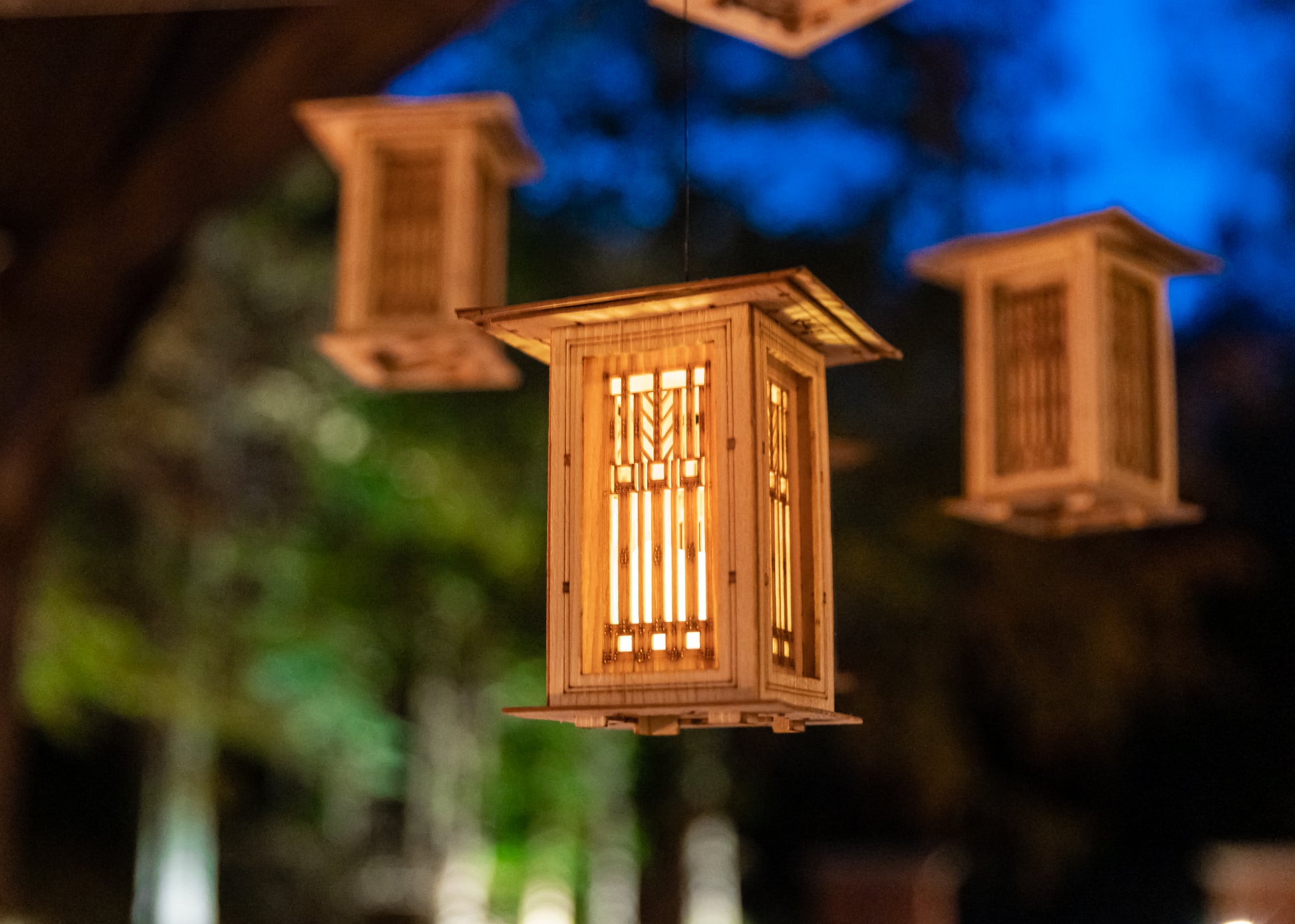illuminated Arts and Crafts lantern hanging outdoors against an evening sky