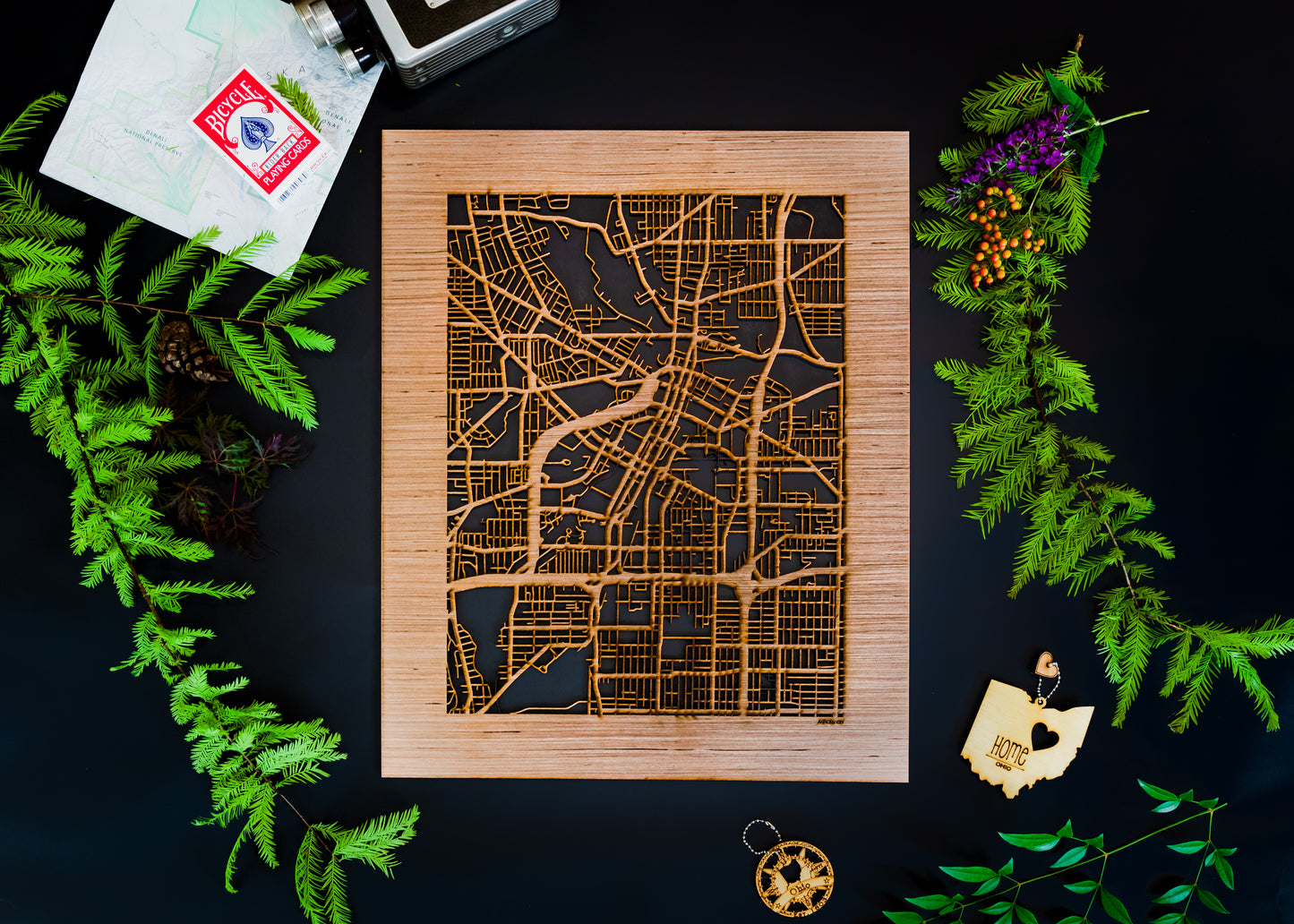 Wooden city map on a dark surface with greenery