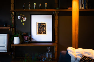 Framed artwork on a shelf with decorative items in a dimly lit room