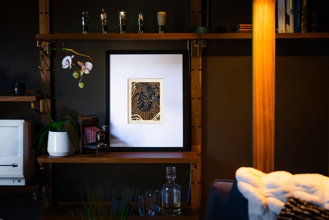 Framed artwork on a shelf with decorative items in a dimly lit room