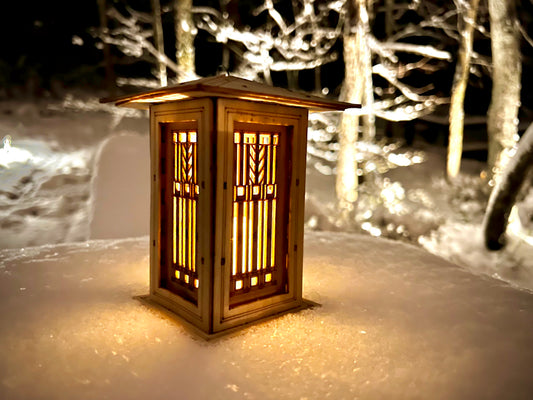 Prairie style wooden lantern glowing warmly in snow with Arts and Crafts inspired architectural details