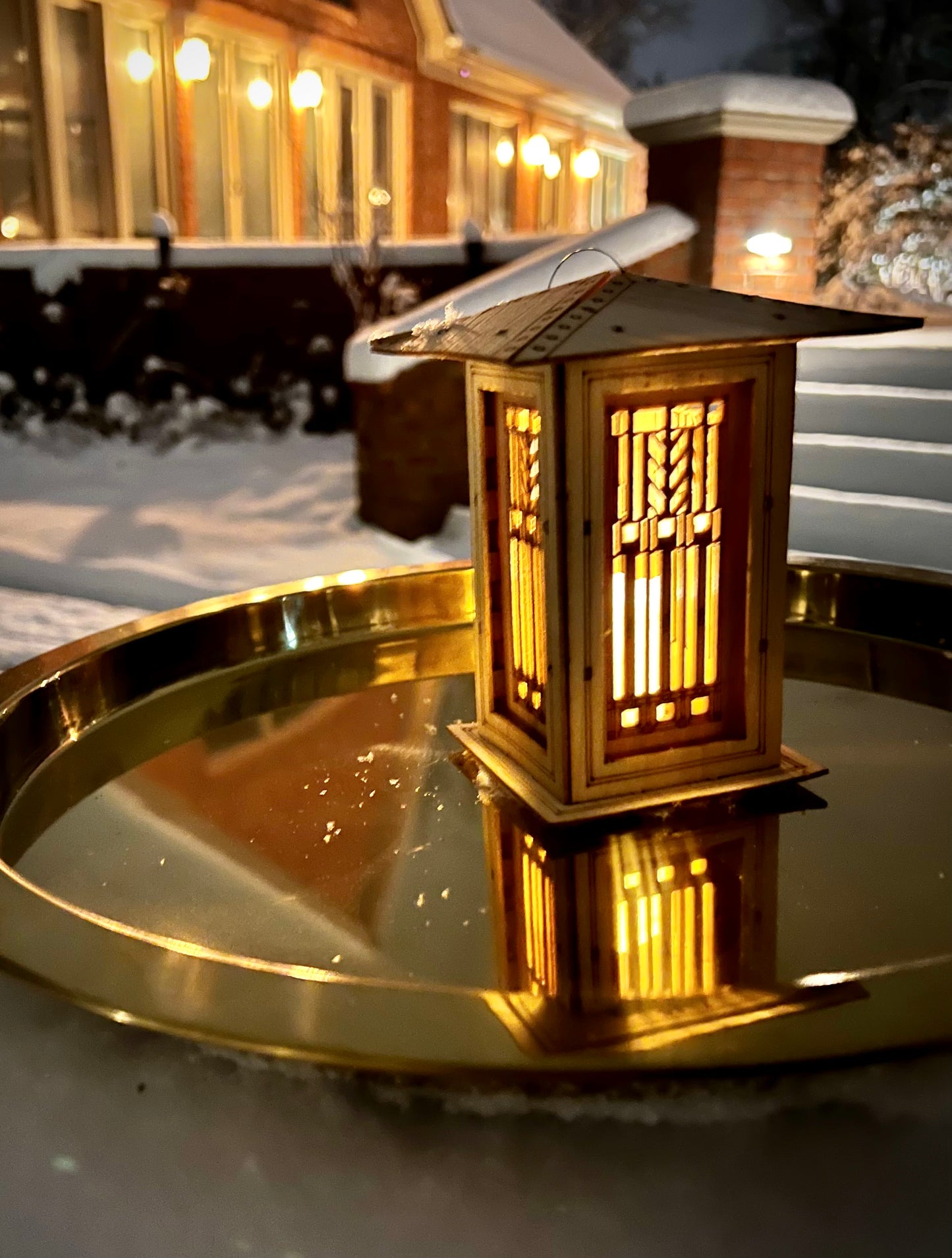 Arts and Crafts inspired lantern reflected on metal tray with warm candlelit glow
