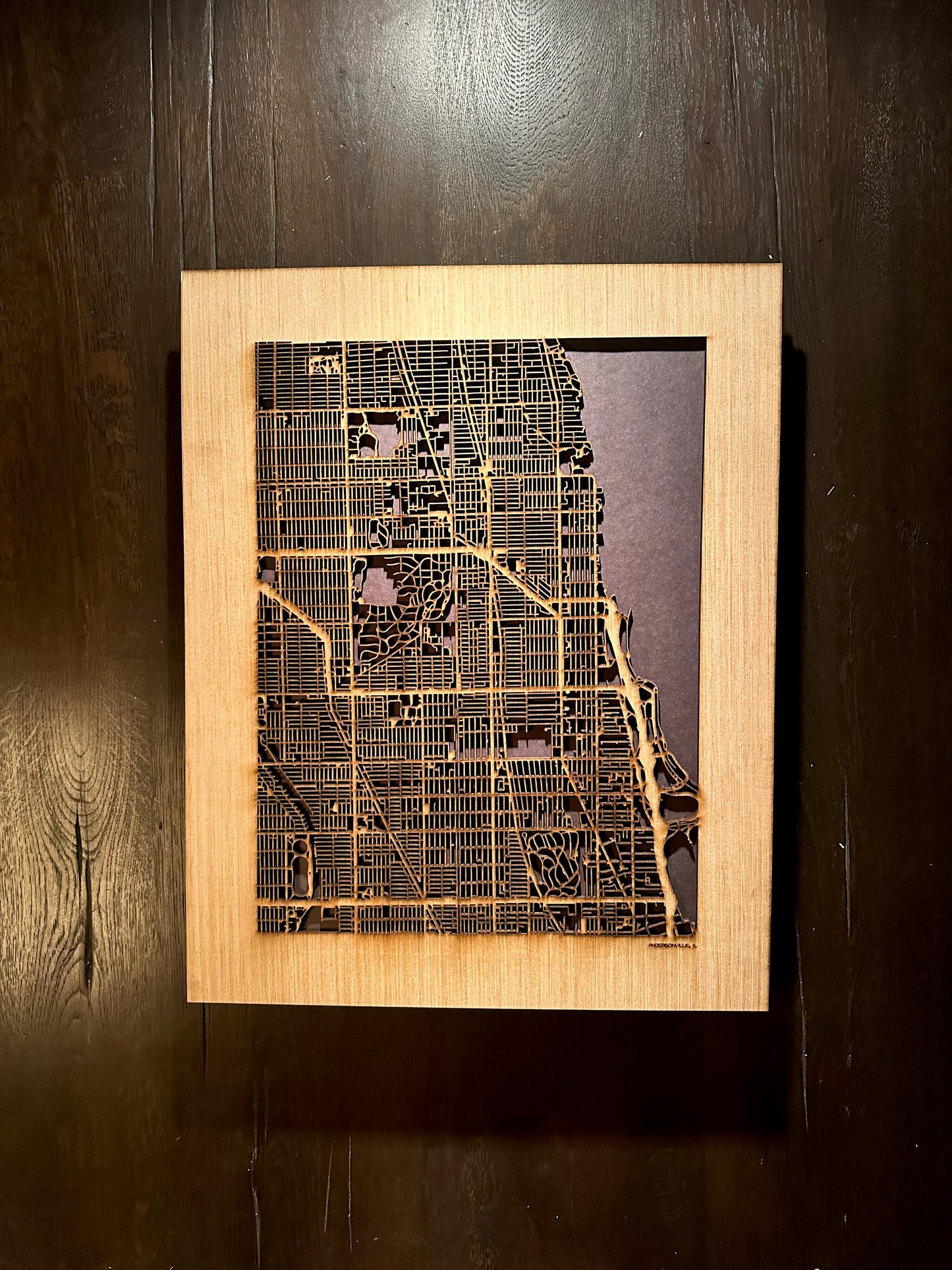 Framed wooden map of a city on a dark wooden surface