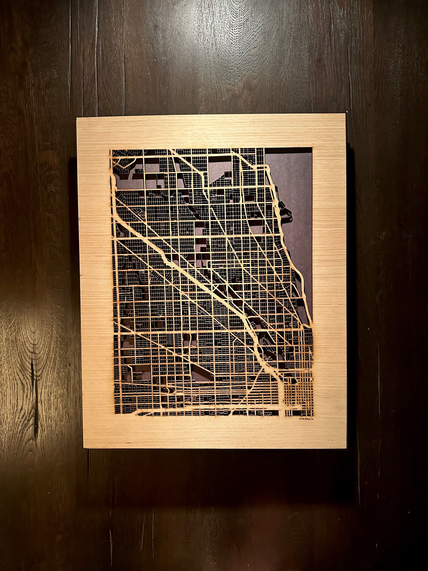 Wooden framed map of a city on a dark wooden wall