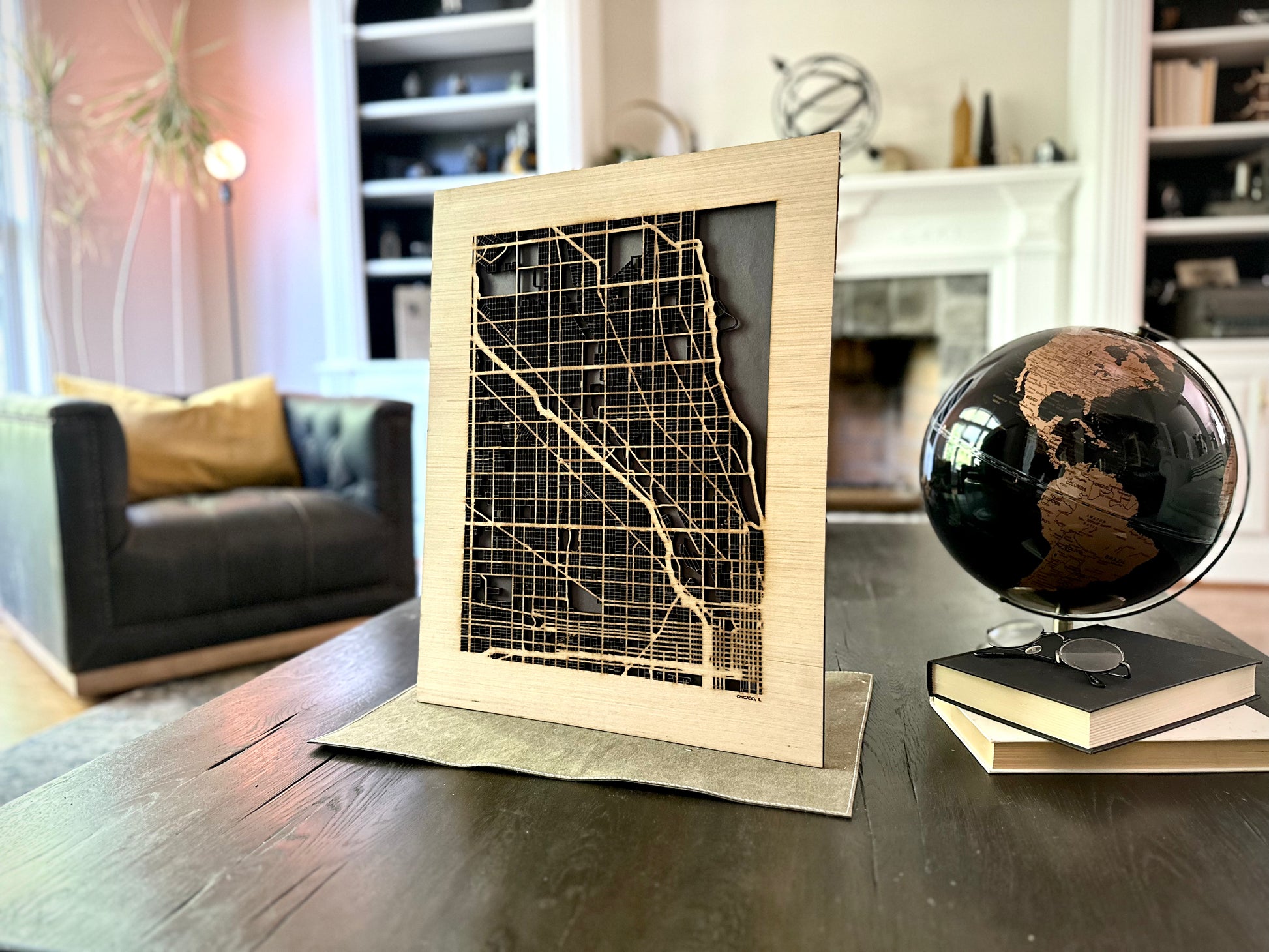 Wooden city map in a frame on a table with a globe in the background.