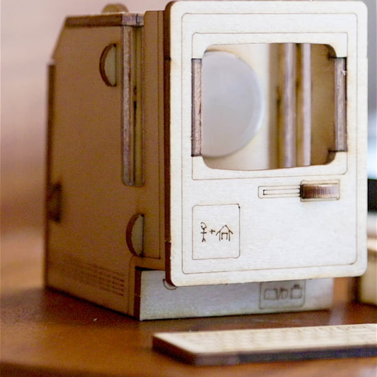 miniature vintage computer charging dock holding Apple Watch on wooden desk