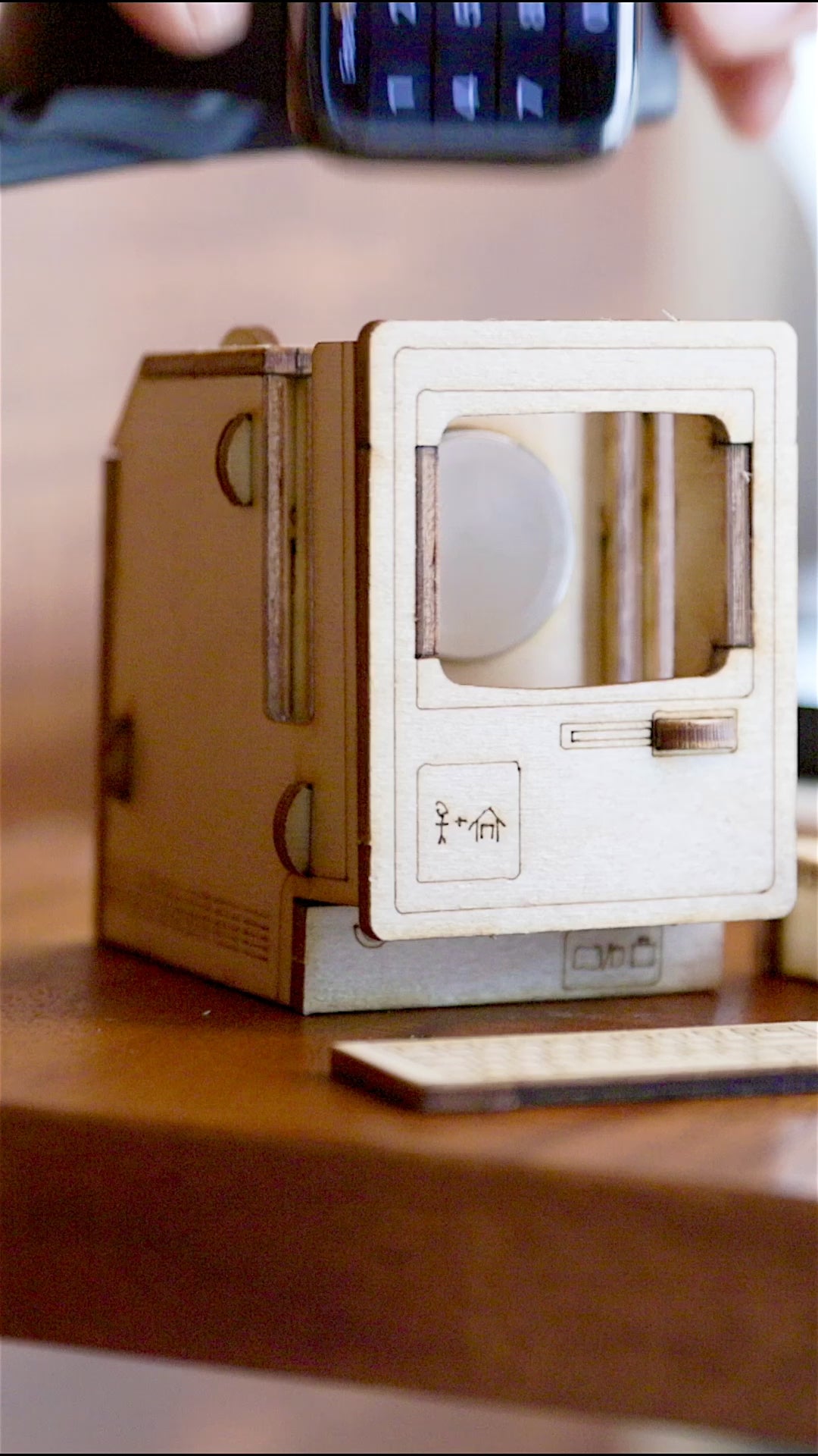 miniature vintage computer charging dock holding Apple Watch on wooden desk