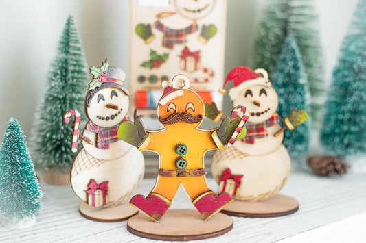 DIY Christmas ornament kit featuring painted gingerbread man and snowman decorations in a festive holiday display
