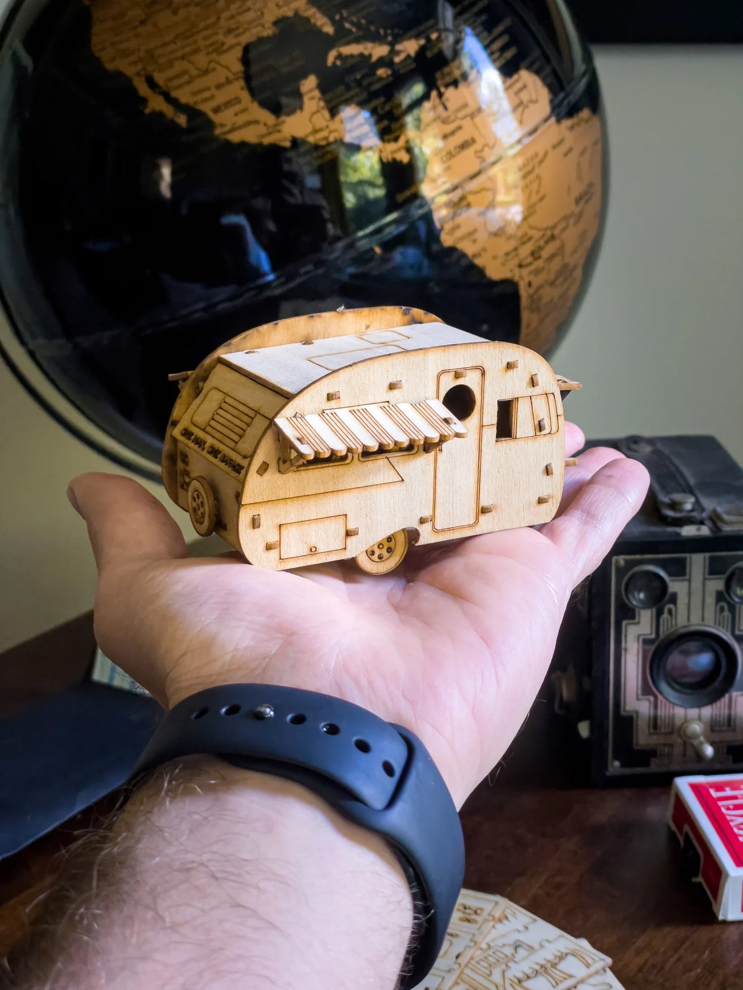 unfinished wooden mini camper held in hand showing natural wood DIY kit version