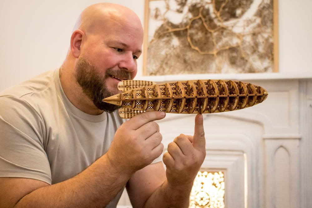 A man holding a miniature wooden model of a 1929 Dirigible Airship.