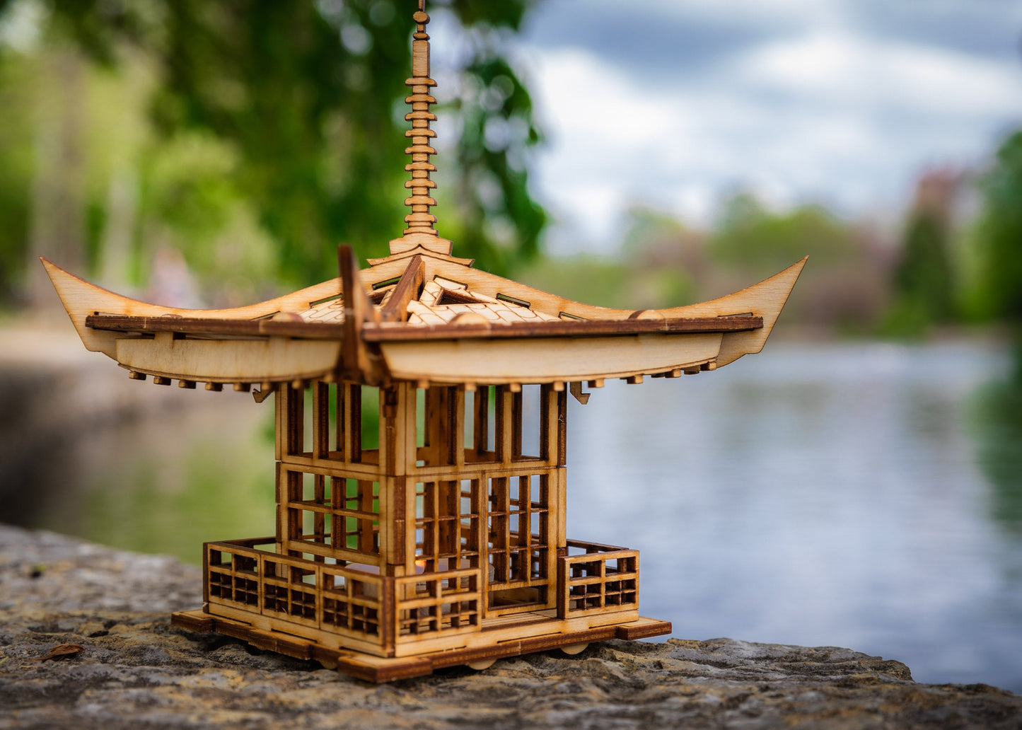 Wooden pagoda lantern placed on stone outdoors with natural background