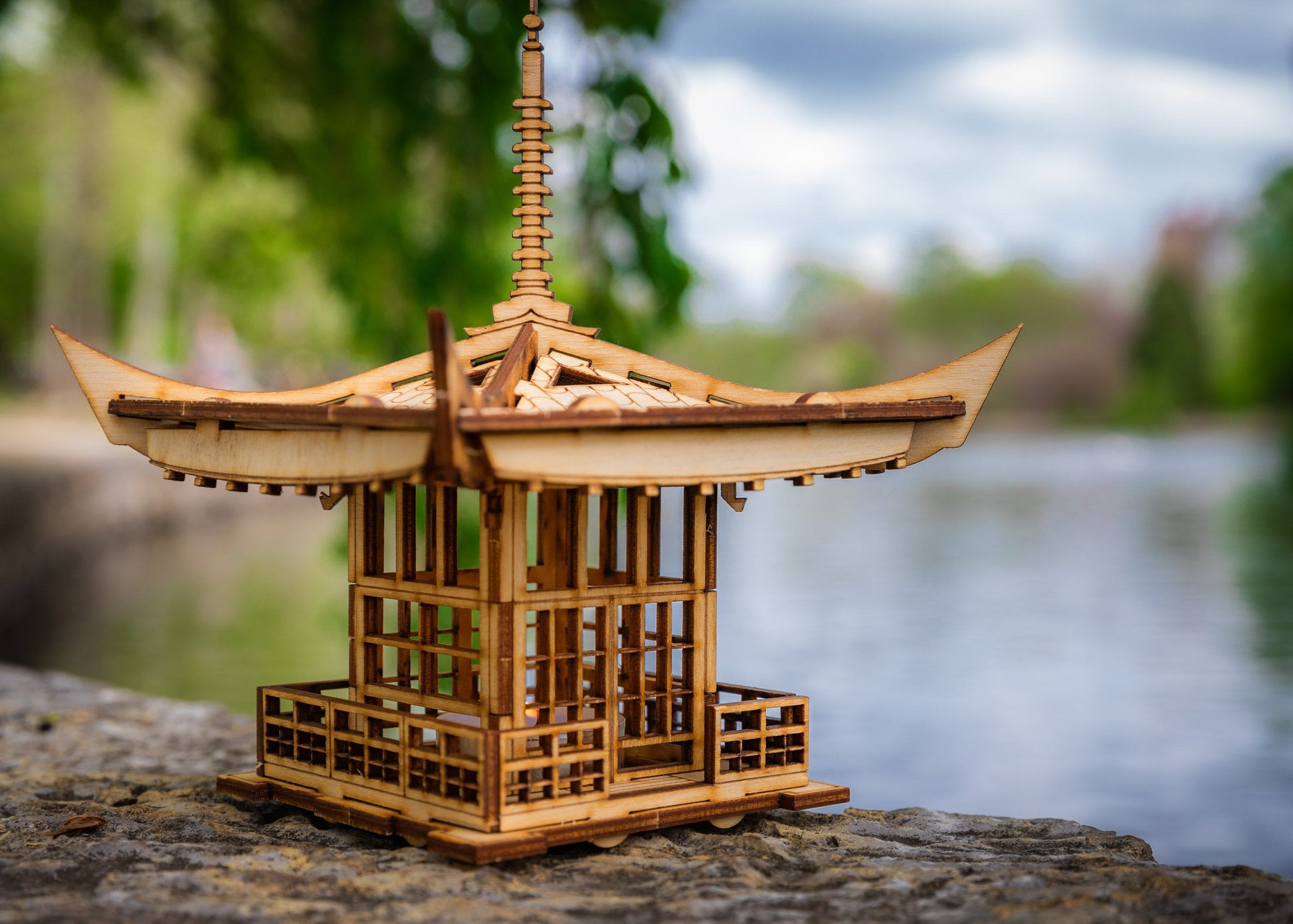 Wooden pagoda lantern placed on stone outdoors with natural background
