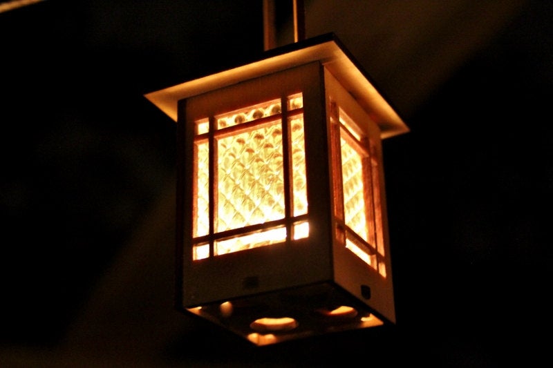 Craftsman-inspired wooden lantern glowing with warm light through patterned window screens