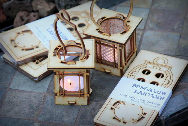 Craftsman Bungalow style wooden lantern kits with clear prism windows and a removable hook, displayed on a table with one lantern lit by a candle.